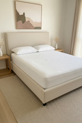 A white striped fitted sheet set on a bed with a dark gray upholstered frame, two white pillows, and black bedside tables in a bedroom setting.
